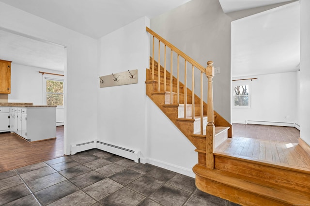 stairway with wood finished floors, baseboards, and baseboard heating