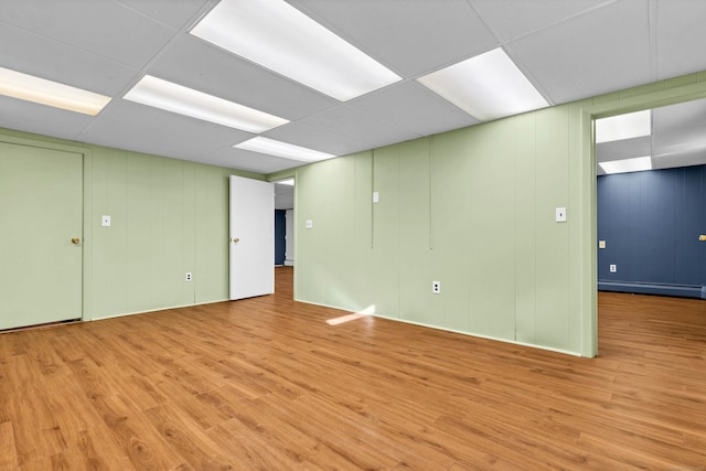 interior space featuring a baseboard heating unit, a paneled ceiling, and wood finished floors