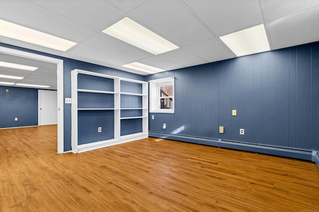 interior space with a baseboard radiator, a paneled ceiling, and wood finished floors