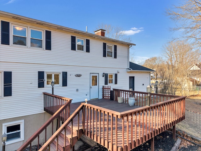 back of house featuring a wooden deck and a chimney