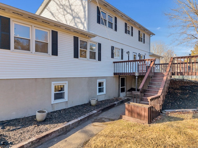 back of house featuring stucco siding, stairway, and a wooden deck