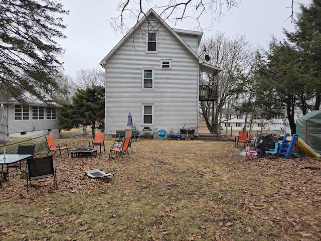back of house featuring an outdoor fire pit and a balcony
