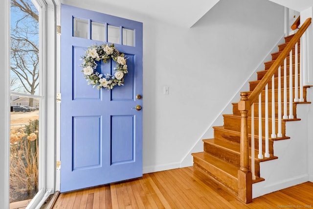 foyer entrance featuring stairs, baseboards, and wood-type flooring