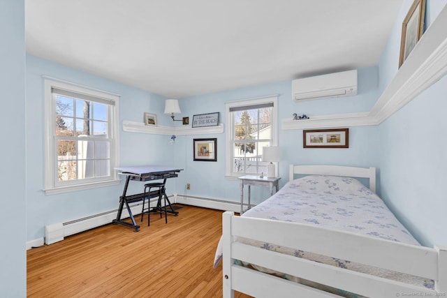 bedroom featuring a baseboard heating unit, baseboards, a wall mounted air conditioner, baseboard heating, and wood finished floors