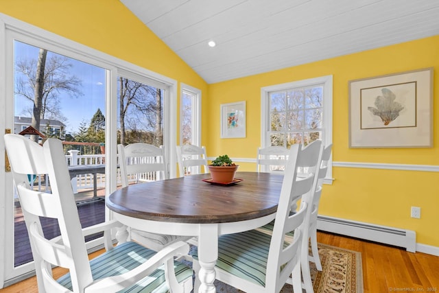 dining room featuring a wealth of natural light, light wood-type flooring, and vaulted ceiling