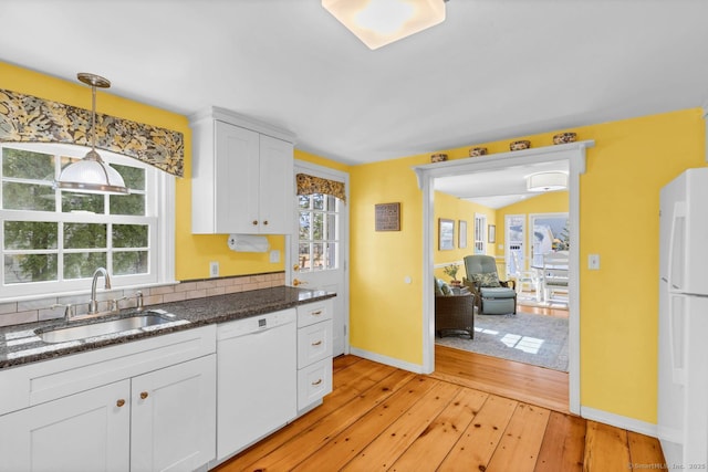 kitchen featuring dark countertops, light wood-type flooring, white appliances, white cabinetry, and a sink