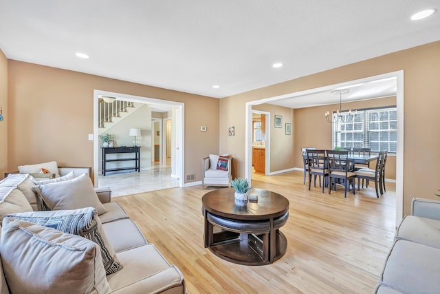 living area with visible vents, baseboards, recessed lighting, light wood-style floors, and a notable chandelier