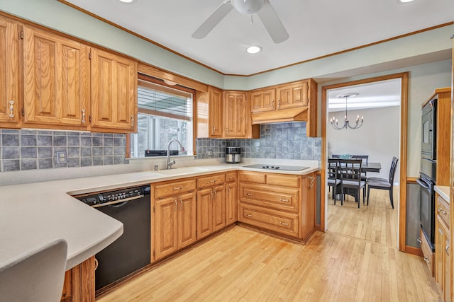 kitchen with a sink, black appliances, light countertops, light wood-style floors, and ceiling fan with notable chandelier