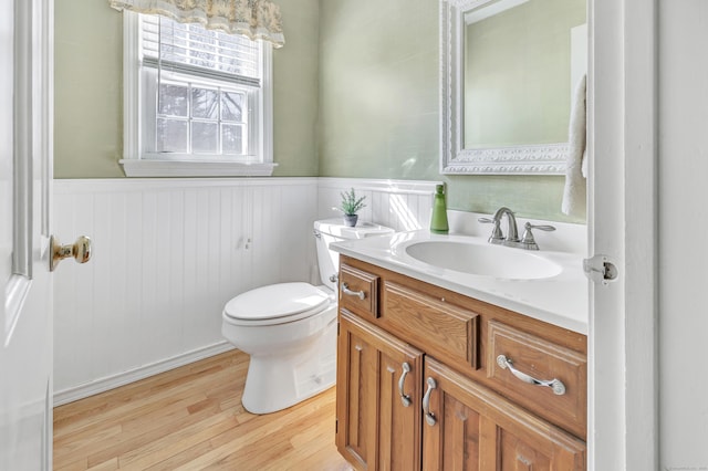 bathroom featuring a wainscoted wall, toilet, wood finished floors, and vanity