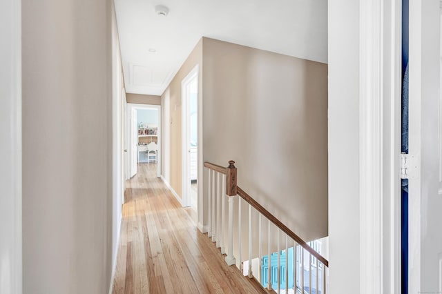 hall featuring an upstairs landing, light wood-style flooring, and attic access