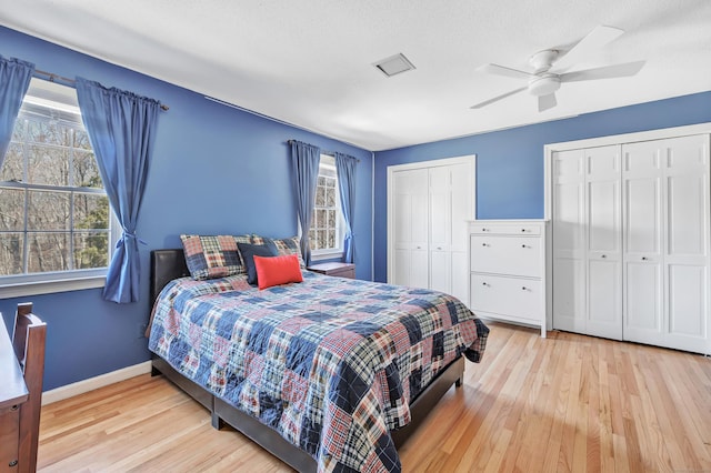 bedroom featuring multiple windows, two closets, and wood finished floors