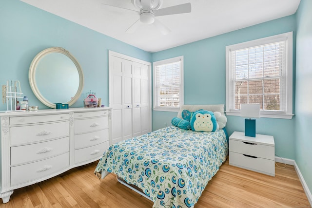 bedroom with ceiling fan, light wood-style floors, a closet, and baseboards