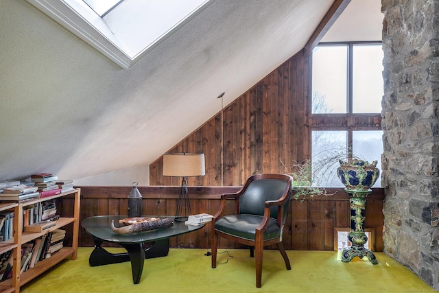 sitting room featuring a textured ceiling, wood walls, carpet flooring, and vaulted ceiling