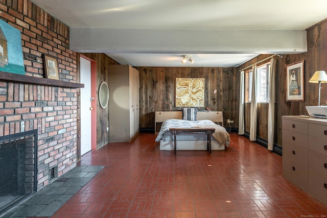 bedroom with beam ceiling, wooden walls, a brick fireplace, and brick floor