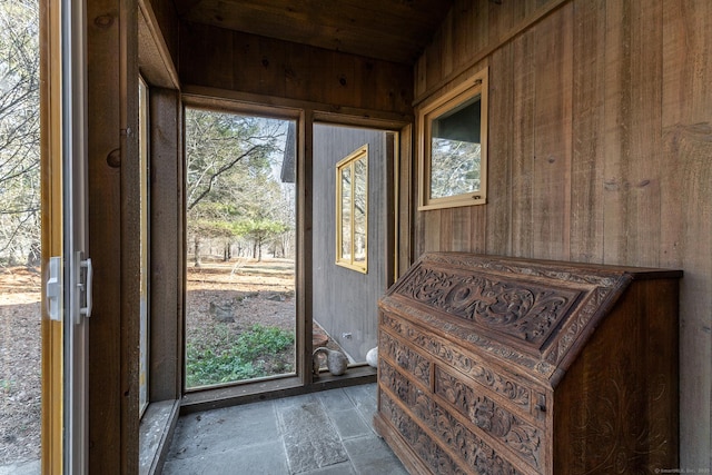 doorway featuring wood walls, wood ceiling, and stone finish floor