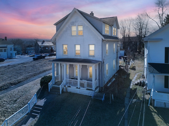 rear view of house featuring a porch and a chimney