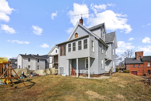 back of house featuring entry steps, a chimney, and a yard