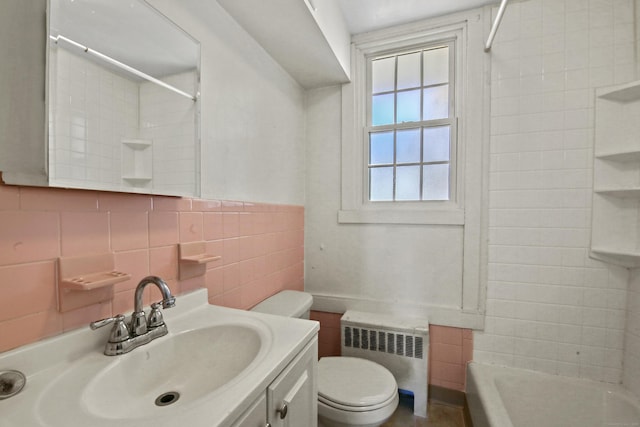 full bath with radiator, tile walls, vanity, and toilet