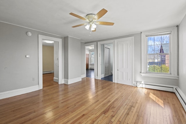 empty room featuring ceiling fan, a baseboard radiator, baseboards, and hardwood / wood-style floors