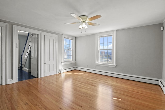 unfurnished bedroom with a ceiling fan, wood finished floors, and a baseboard radiator