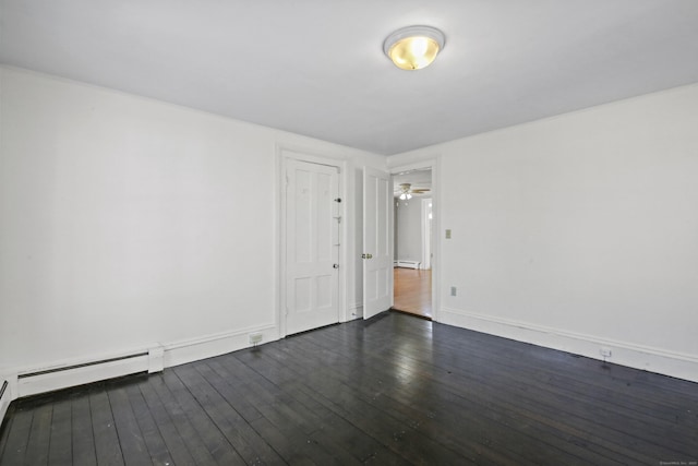 spare room featuring a baseboard heating unit, dark wood finished floors, baseboards, and a ceiling fan