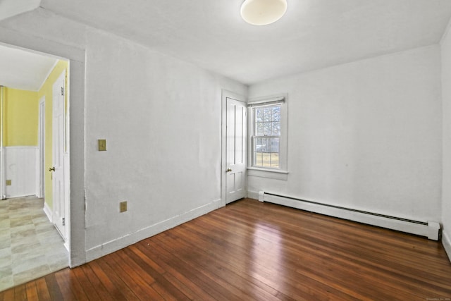 empty room featuring a baseboard heating unit and hardwood / wood-style floors