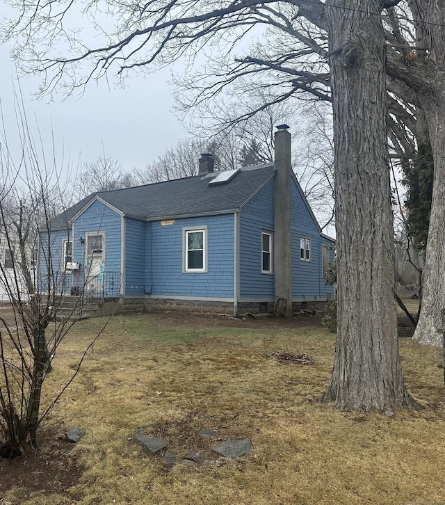 view of property exterior with a yard, roof with shingles, and a chimney