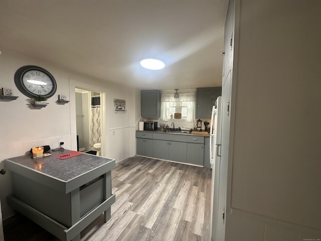 kitchen featuring stainless steel microwave, light wood-style floors, gray cabinets, and a sink