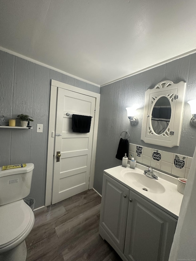 bathroom with tasteful backsplash, toilet, wood finished floors, and vanity