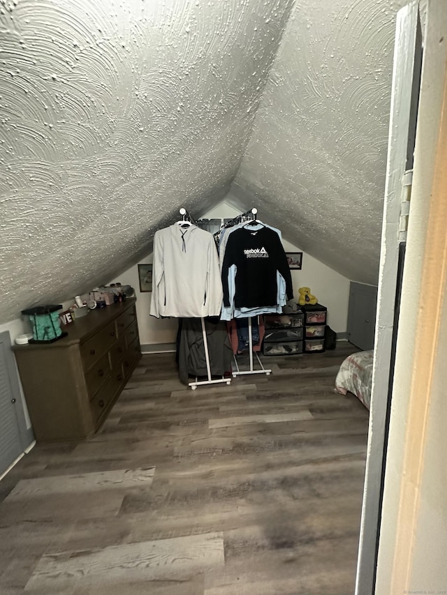 additional living space with a textured ceiling, lofted ceiling, and wood finished floors