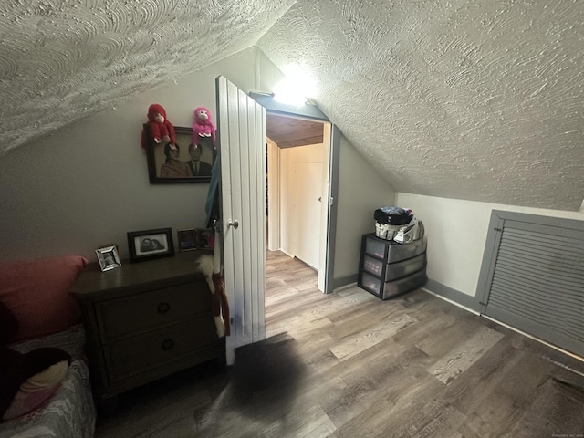 bonus room with vaulted ceiling, wood finished floors, baseboards, and a textured ceiling