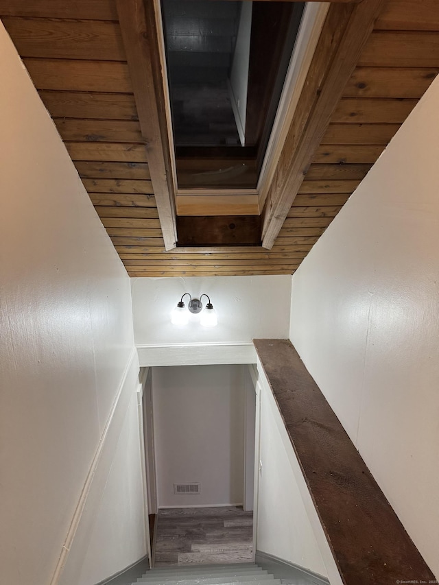 staircase with visible vents, beamed ceiling, wooden ceiling, and wood finished floors