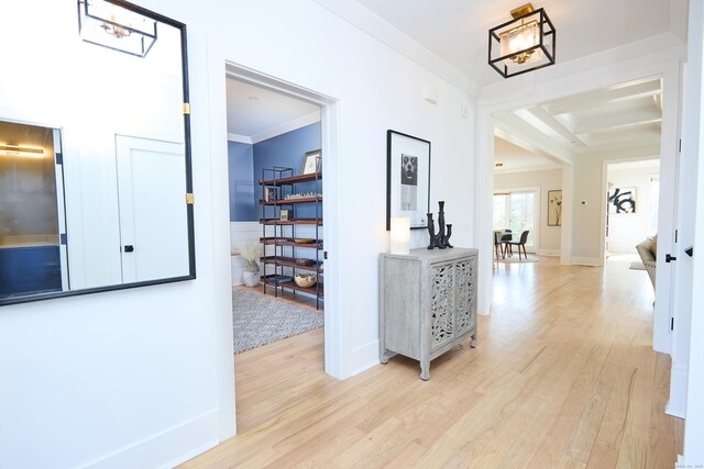 hallway featuring crown molding, baseboards, and light wood finished floors