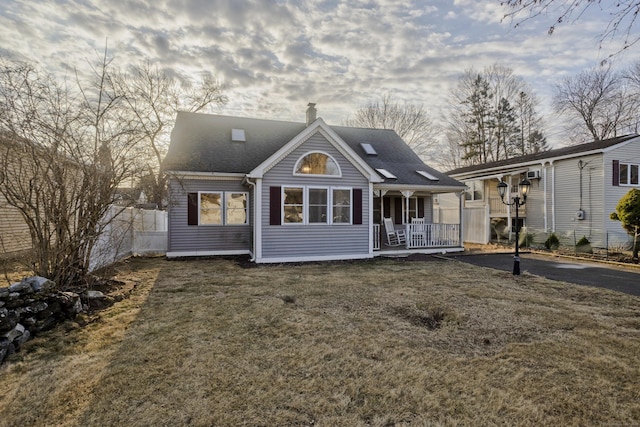 rear view of property with fence, a yard, covered porch, a shingled roof, and a chimney