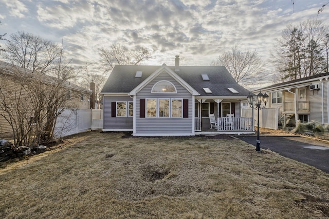 back of house with driveway, fence, a yard, covered porch, and a shingled roof