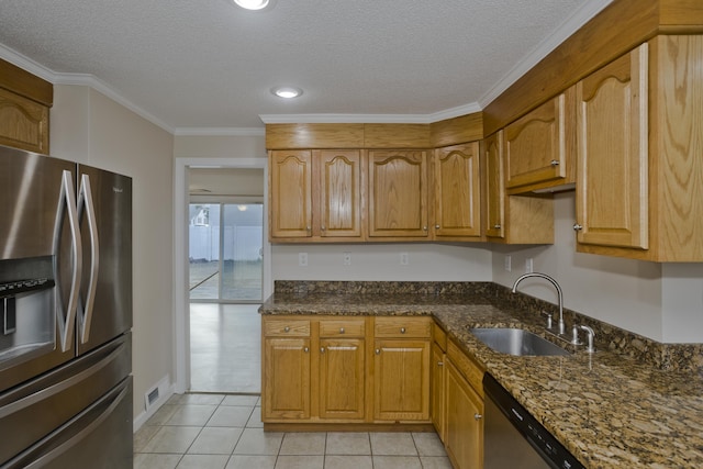 kitchen with ornamental molding, a sink, dark stone countertops, appliances with stainless steel finishes, and light tile patterned flooring