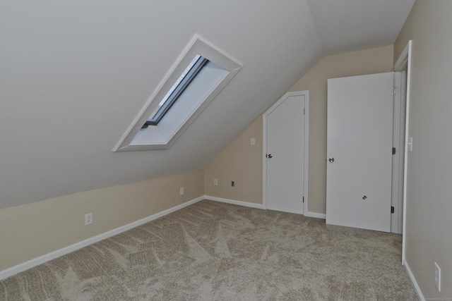 additional living space with baseboards, vaulted ceiling with skylight, and carpet