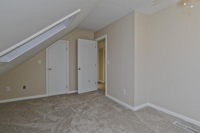 bonus room with lofted ceiling with skylight, carpet flooring, baseboards, and visible vents