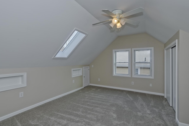 bonus room featuring lofted ceiling with skylight, carpet flooring, a ceiling fan, and baseboards