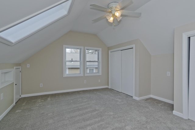 additional living space with baseboards, lofted ceiling with skylight, carpet, and a ceiling fan