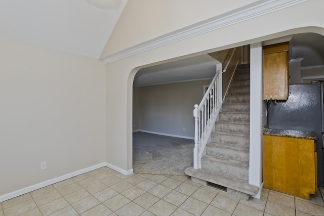 staircase with lofted ceiling, ornamental molding, arched walkways, tile patterned flooring, and baseboards