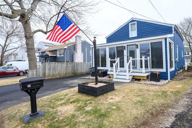 view of front of home featuring a sunroom and fence