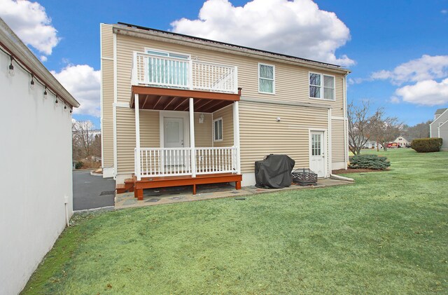 back of house featuring a lawn and a balcony
