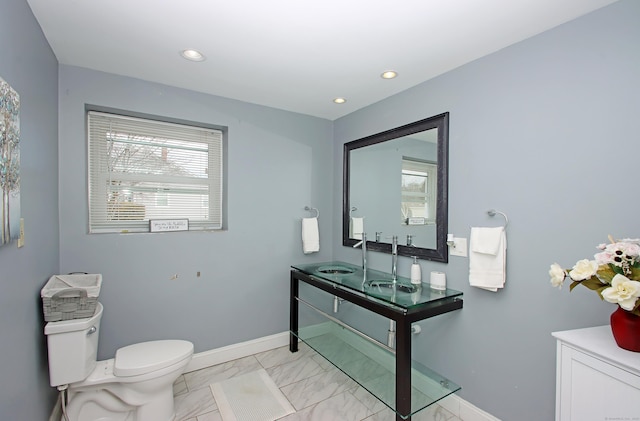 bathroom featuring toilet, baseboards, a wealth of natural light, and a sink