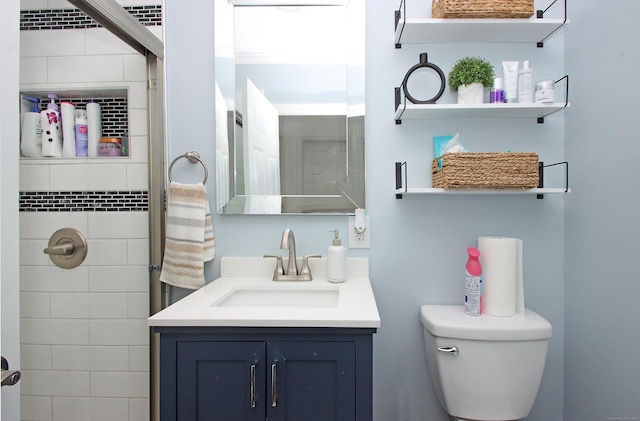 full bathroom featuring a tile shower, toilet, and vanity
