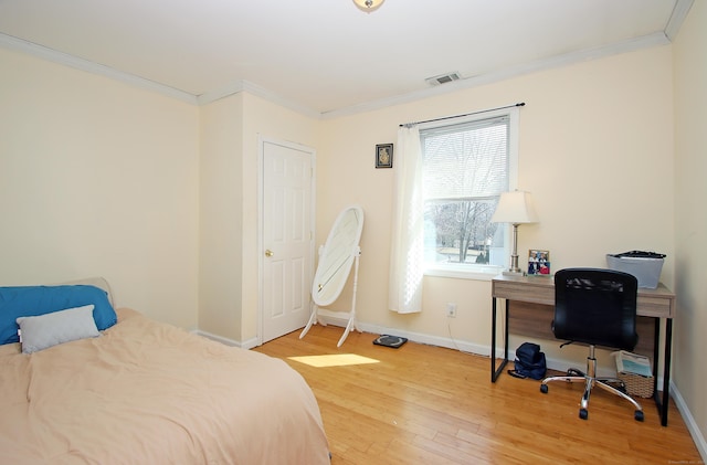 bedroom featuring visible vents, wood finished floors, baseboards, and ornamental molding