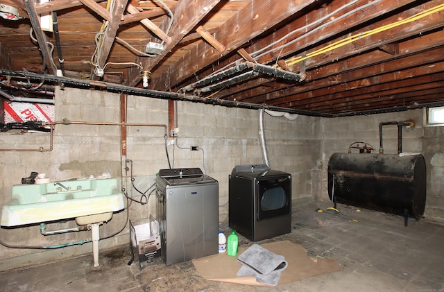 unfinished below grade area featuring a sink, heating fuel, and washing machine and clothes dryer