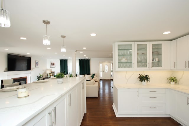 kitchen featuring light stone counters, recessed lighting, dark wood-type flooring, glass insert cabinets, and open floor plan