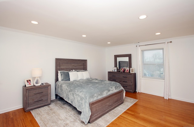 bedroom with light wood finished floors, recessed lighting, crown molding, and baseboards