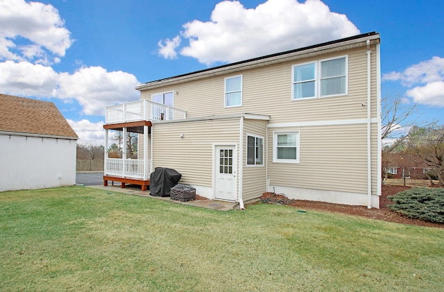 rear view of property with a balcony and a lawn